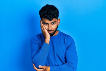 Arab man with beard wearing casual blue sweater thinking looking tired and bored with depression problems with crossed arms.