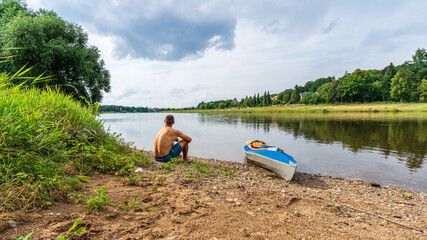Fototapeta na wymiar A fit man next to a folding kayak during a paddle trip on the Elbe river