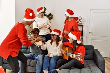 Group of young people celebrating christmas singing carol song at home.