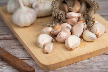 Garlic bulb and Garlic cloves on wooden chopping board.