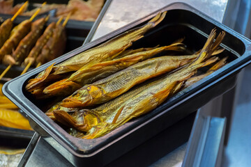 smoked fish with sharp teeth in a plastic container on a shop window