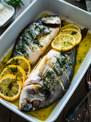 Roast sea bream  in cooking pan on wooden table

