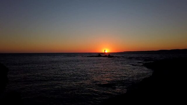 Motion timelapse Sunset in Calasetta sea behind Mangiabarche`s lighthouse, Sardinia, Italy