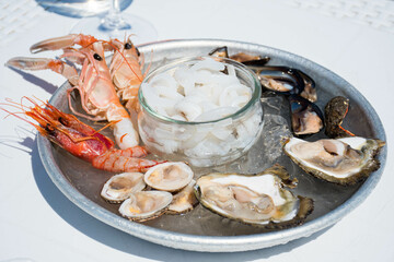 Plate of raw fresh sea fruit or food, ready to eat with prawns, shrimps, oysters, mussels, shells,...