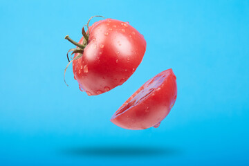 A ripe tomato cut in the air on a blue background
