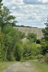 Fototapeta na wymiar Route rocailleuse de campagne entre végétation sauvage sur les collines dominant le bourg de Champagne au Périgord Vert 