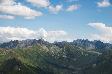 Aerial view of polish tatra peaks in the foreground, highest Slovakian peaks visible in the background with blue cloudy sky