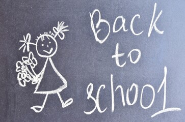 Drawing with chalk, a girl with bouquets of flowers drawn in chalk on a black chalkboard with the inscription back to school