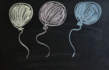 three air multicolored balloons drawn with chalk on a black board. Copy space