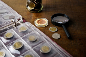 Obraz na płótnie Canvas Old collectible coins on a wooden table. Dark background. Banner. Numismatics, Coins in the album. Selective focus. 