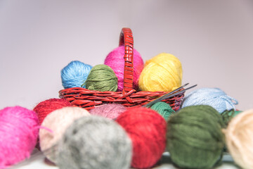 Conjunto de ovillos de hilo de lana de diferentes colores y tamaños en una cesta de mimbre. Agujas de tejer. Crochet, ganchillo. Bolas de hilo. Madejas - obrazy, fototapety, plakaty