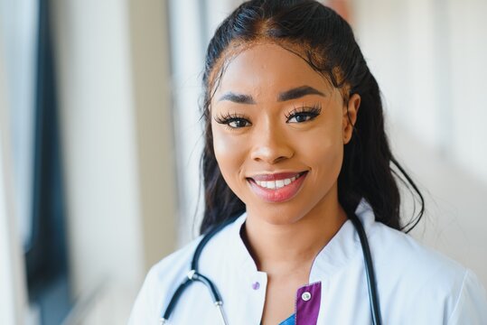 Portrait confident African American female doctor medical professional writing patient notes isolated on hospital clinic hallway windows background. Positive face expression