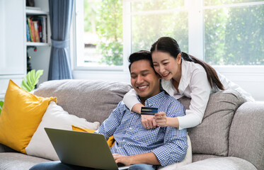 Pleasant family couple sitting looking at laptop screen. Happy young  spouse web surfing, making purchases online or booking flight tickets.