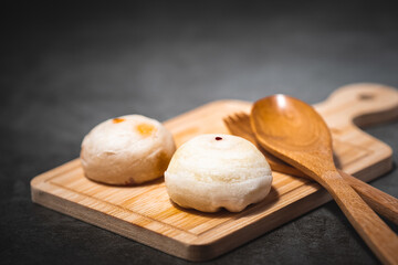 Traditional Chinese pastry with wooden spoon on plate against dark background for food and bakery concept