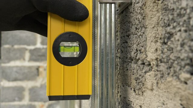 Balance ruler. Magnetic water level horizontal, vertical ruler. Man measuring deviation of the metal profile frame on the wall with a spirit level.