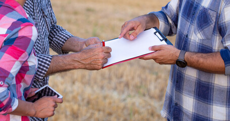 Farmers signing documents in field