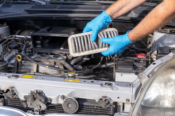 Automotive technician holding used dirty engine air filter for a car