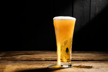 Beer glass with white beer foam on wooden floor dark wood background
