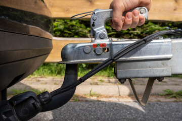 woman's hand checks the fixation of the trailer closed hitch lock handle on the towing ball towbar...