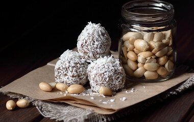 Vegan balls with dates, peanut butter and coconut on dark moody background, healthy protein homemade dessert for christmas holidays, closeup, copy space, vertical