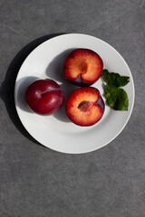 Cuted plums on a white plate and dark background