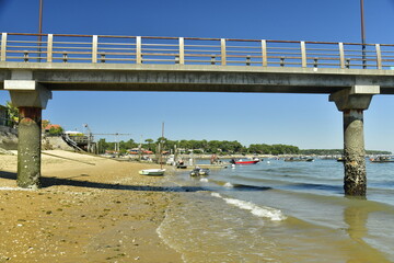 La plage à marée basse et les pilotis en béton du ponton d'embarquement à Canon dans la baie...