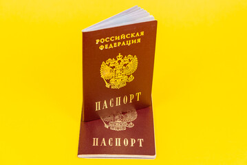 Russian passport stands in a semi-expanded form on another passport.