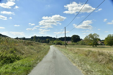 Fototapeta na wymiar Petite route secondaire de campagne traversant prairies et champs au bourg de Champagne-et-Fontaine au Périgord Vert 