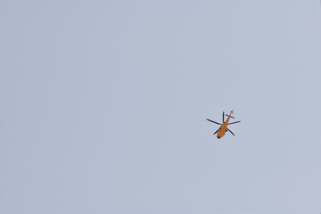 High view of a yellow helicopter flying with clear blue sky