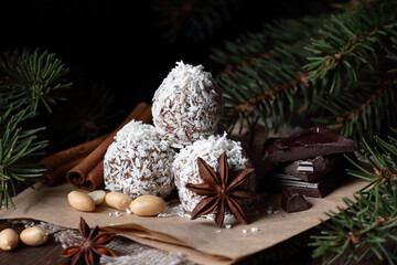 Christmas vegan balls with dates, peanut butter and coconut on dark moody background, healthy protein homemade dessert for christmas holidays, closeup, copy space, vertical