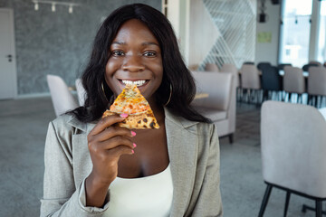 african american woman in business suit eating pizza.