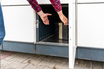 Pickup parcel. Courier box in woman hands at post delivery automat terminal. Self service post terminal and parcel delivery concept.