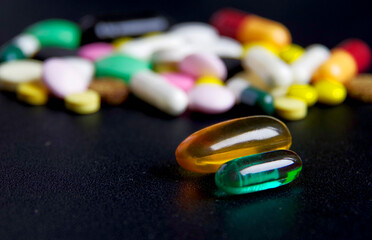 Medicines in the form of capsules and tablets on a dark surface.