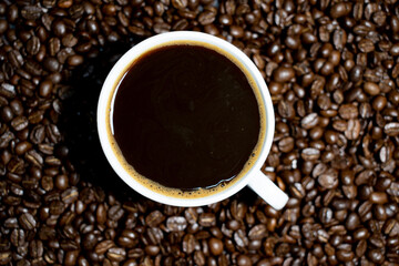 Coffee cup top view on roasted coffee beans background