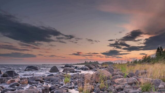 4K time lapse of Magnificent Soft and colorful sunset by the seaside stone. Beautiful cloud movement with seashore stones. Gradual light reduction.