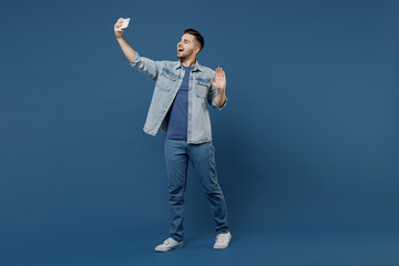 Full size length body happy young brunet man 20s wears denim jacket talk speak on mobile cell phone...