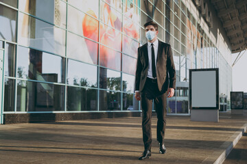 Bottom view full body young traveler businessman man in black dinner suit sterile mask standing outside at international airport terminal look aside. People air flight business trip lifestyle concept.