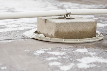 Concrete foot holding a covered lightning conductor wire on the roof. - obrazy, fototapety, plakaty
