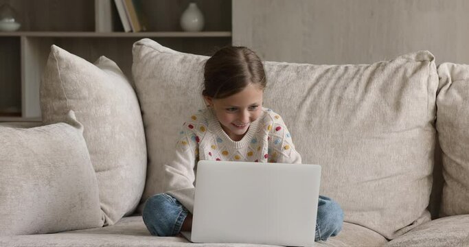 Little girl sit on sofa at home with laptop studying online use internet resources, learn educational blog. Young gen and modern tech usage for development and fun, parental control software concept