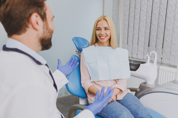 Young man dentist doctor wear white gown talk speaking with patient consulting woman sitting at...