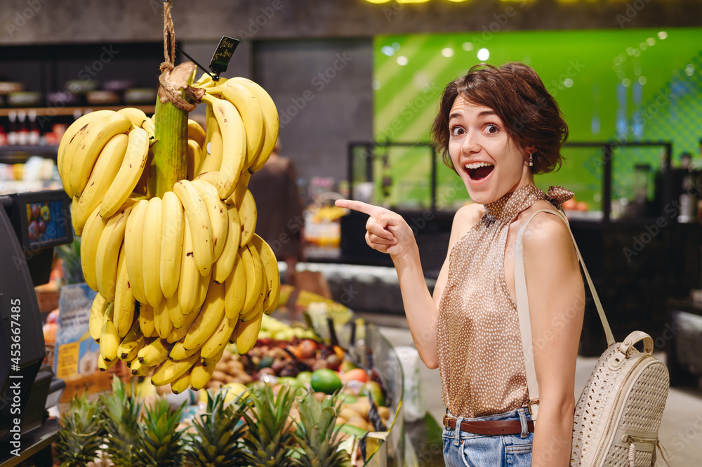 Wall mural young surpirsed happy woman in casual clothes shopping at supermaket greengrocery store buy choosing