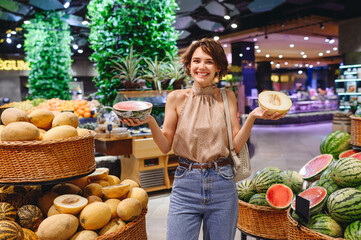 Young smiling happy woman 20s in casual clothes shopping at supermaket greengrocery store buy...