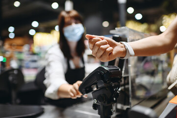 Cropped close up woman hand arm shopping at supermaket put smart watch to modern bank payment...
