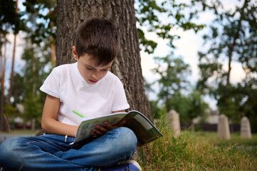 Fototapeta premium Children go back to school. Start of new school year after summer holidays. Adorable handsome schoolboy , elementary aged kid with doing homework during recreation between lessons on first school day