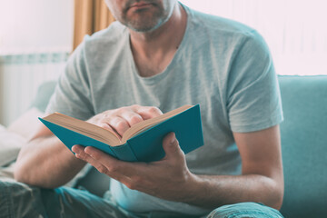 Man reading book at home, enjoying a good read alone