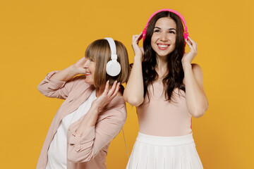 Two young cheerful happy daughter mother together couple women wear casual beige clothes headphones...