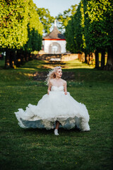 beautiful, blond bride running in the park with a big, white dress and waving hair