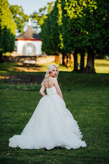 beautiful, blond bride standing in the park with a big, white dress