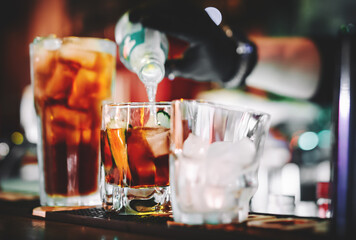 hands of a bartender with black gloves making cocktail on a bar counter.