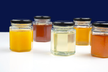 jars with different types and colors of honey on a white background. organic vitamin food